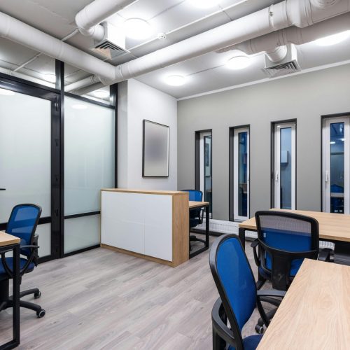 Interior of new contemporary spacious workplace with wooden desks and blue office chairs