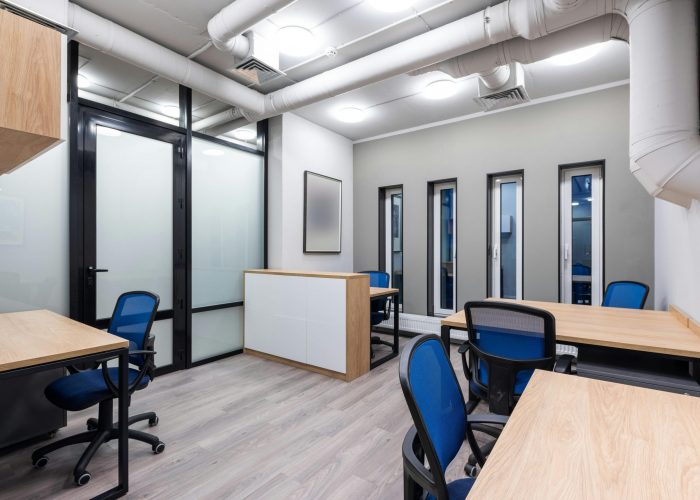 Interior of new contemporary spacious workplace with wooden desks and blue office chairs